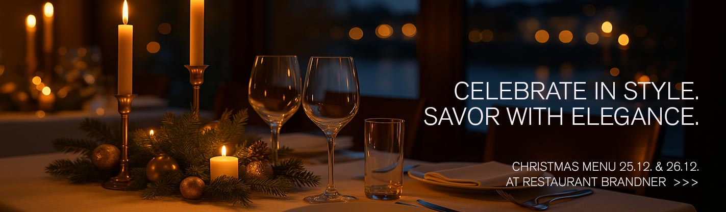 Festive table with candles and river view for the Christmas menu at Restaurant Brandner Regensburg