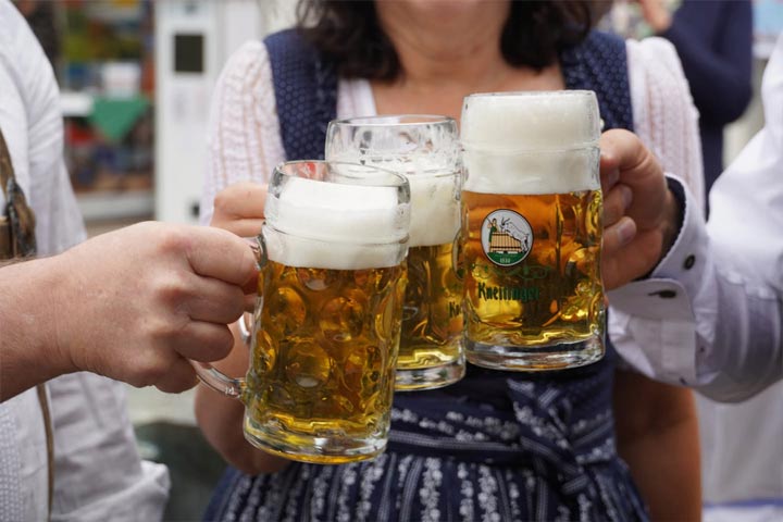 Hände stoßen mit gefüllten Bierkrügen beim Regensburg Fest 2026 in Berlin an.